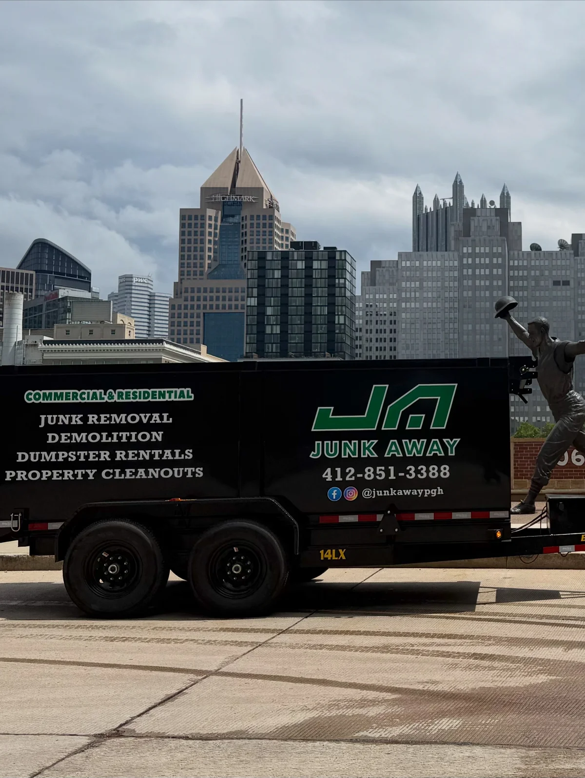 Junk Away dump trailer with the Pittsburgh skyline behind it