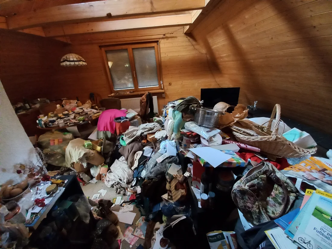 Cluttered living room filled with furniture and household belongings awaiting a cleanout